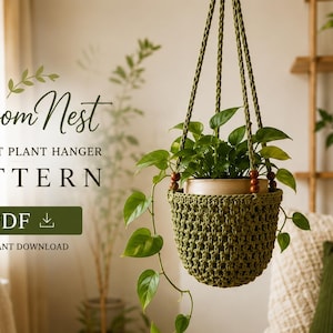 Puede incluir: Un colgador de plantas de ganchillo verde que sostiene una planta en maceta con hojas colgantes. El colgador presenta un diseño texturizado de punto abierto con cuentas de madera en la parte superior. El texto dice: Bloom Nest CROCHET PLANT HANGER PATTERN PDF.