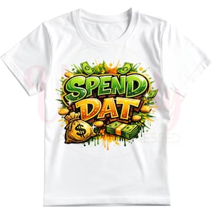 May include: White t-shirt featuring the phrase "SPEND DAT" in a vibrant, graffiti-style design. The graphic includes green and gold lettering, dollar signs, money bags, and stacks of cash, creating a bold and eye-catching statement.