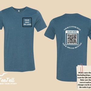 May include: Blue t-shirt with customizable text or logo area on the front and a QR code on the back. The back of the shirt includes the text "YOUR CUSTOM TEXT", "SCAN HERE", and "YOUR SPECIAL MESSAGE". The shirt also has the logo "TeeTell WEAR YOUR STORY".