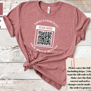 May include: Heather mauve t-shirt with a QR code graphic. The shirt features the text "YOUR CUSTOM TEXT", "SCAN HERE", and "YOUR SPECIAL MESSAGE". A small paper with instructions is attached to the shirt.