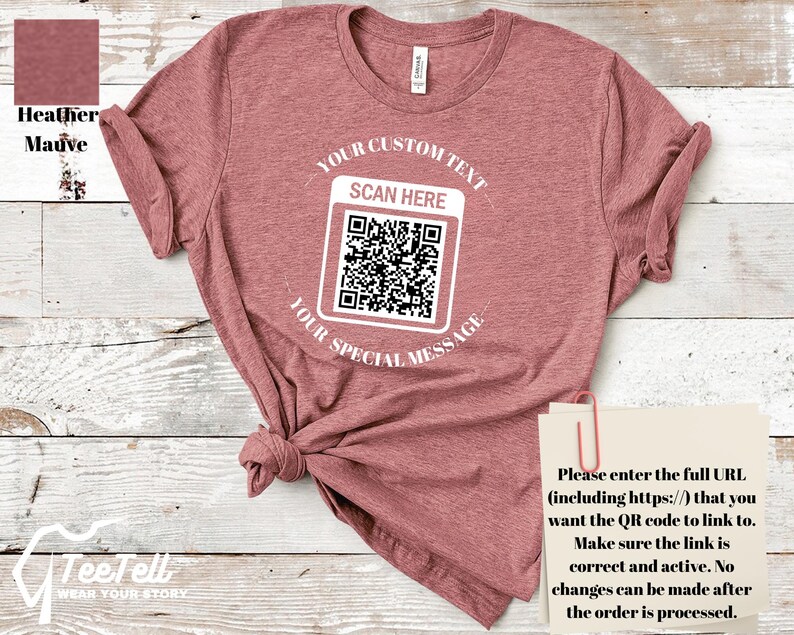 May include: Heather mauve t-shirt with a QR code graphic. The shirt features the text "YOUR CUSTOM TEXT", "SCAN HERE", and "YOUR SPECIAL MESSAGE". A small paper with instructions is attached to the shirt.