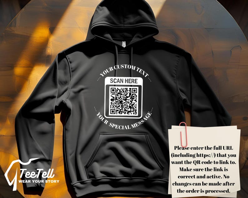 May include: Black hoodie with a front pocket and a hood. The front features a white graphic with a QR code and the text "YOUR CUSTOM TEXT SCAN HERE YOUR SPECIAL MESSAGE". A note with instructions is clipped to the hoodie.