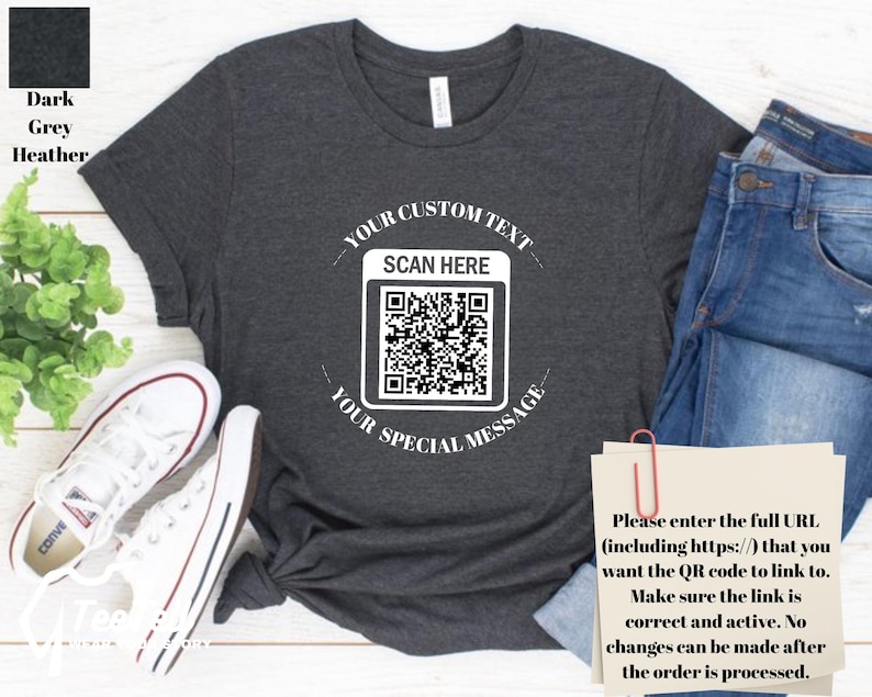 May include: Dark grey heather t-shirt with a white QR code graphic. The text around the QR code reads "YOUR CUSTOM TEXT" and "YOUR SPECIAL MESSAGE". The shirt is paired with blue jeans and white sneakers.
