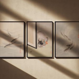 Puede incluir: Tres impresiones artísticas enmarcadas con marcos negros. Las impresiones presentan ilustraciones de estilo japonés de peces y un gato. La obra de arte tiene una paleta de colores suaves y apagados con caracteres japoneses rojos.