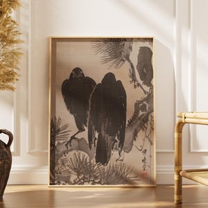 Peut inclure: Impression encadrée représentant deux oiseaux noirs perchés sur une branche, dans le style traditionnel japonais à l'encre. L'œuvre a une palette de couleurs neutres avec un fond beige et un cadre doré. L'impression est exposée à l'intérieur.