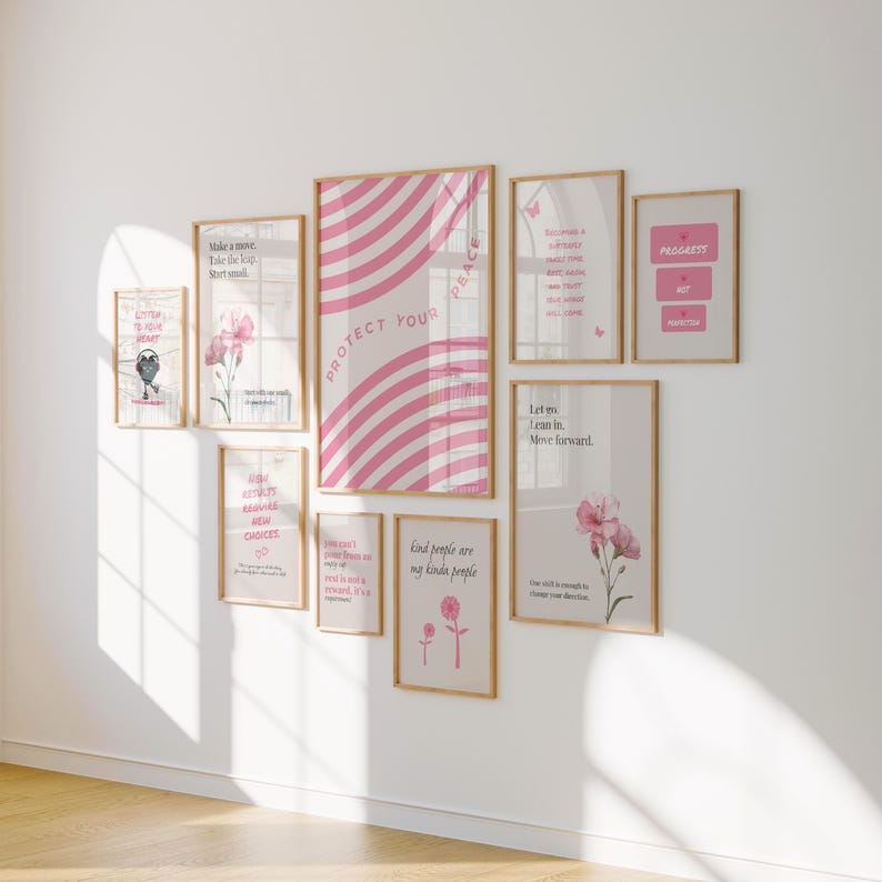 Pu&ograve; includere: Una collezione di stampe artistiche incorniciate di varie dimensioni, disposte su una parete bianca. Le stampe presentano disegni rosa e bianchi, illustrazioni floreali e citazioni ispiratrici. La stampa pi&ugrave; grande recita "PROTECT YOUR PEACE."