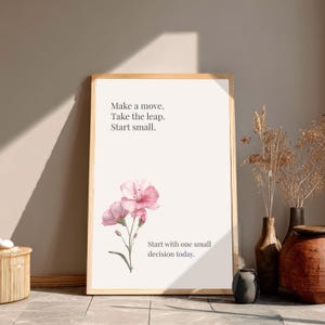 Pu&ograve; includere: Una stampa incorniciata con una cornice in legno chiaro. La stampa presenta il testo "Make a move. Take the leap. Start small." e "Start with one small decision today." Fiori rosa ad acquerello in basso.