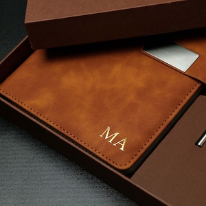 Op de afbeelding: Een bruin leren notitieboek met de initialen "MA" in gouden letters, gepresenteerd in een bijpassende geschenkdoos. Het notitieboek heeft een zilveren metalen sluiting en wordt geleverd met een pen. Een ideaal cadeau.