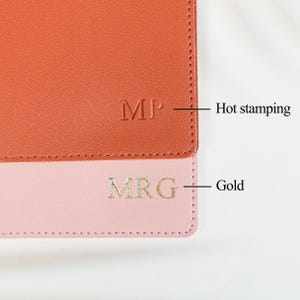 May include: A two-toned leather item featuring an orange section with the embossed text MP labeled as Hot stamping and a light pink section with the gold-colored text MRG labeled as Gold, showcasing two distinct personalization techniques.