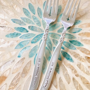 May include: Two silver forks with ornate handles. The forks are engraved with the text "For making fabulous at 50!" and "For making fabulous at 40!"