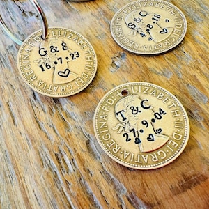 May include: Two gold-colored coin keychains with engraved dates and initials. The coins feature a profile of Queen Elizabeth II and the text "GRATIA DEI" and "REGINA F.D."