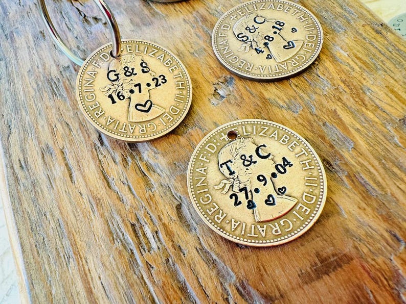 May include: Two gold-colored coin keychains with engraved dates and initials. The coins feature a profile of Queen Elizabeth II and the text "GRATIA DEI" and "REGINA F.D."