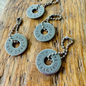 Puede incluir: Cuatro llaveros plateados con cadenas de bolas. Cada llavero es una arandela met&aacute;lica circular con texto estampado. El texto en tres llaveros dice "Fuck Fascism", y uno dice "End Fascism".