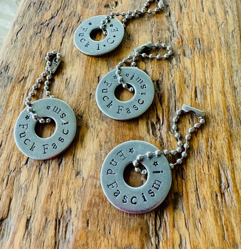 Puede incluir: Cuatro llaveros plateados con cadenas de bolas. Cada llavero es una arandela met&aacute;lica circular con texto estampado. El texto en tres llaveros dice "Fuck Fascism", y uno dice "End Fascism".