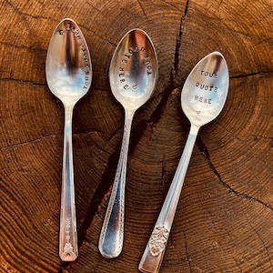 Peut inclure: Trois cuillères en argent avec du texte gravé. Les cuillères ont des manches ornés et sont disposées sur une surface en bois. Le texte sur les cuillères est "Your quote here", "Your quote here" et "Your quote here".
