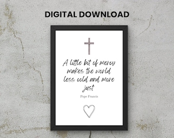 May include: Black framed print with the text "A little bit of mercy makes the world less cold and more just" by Pope Francis. The print includes a cross and a heart symbol.