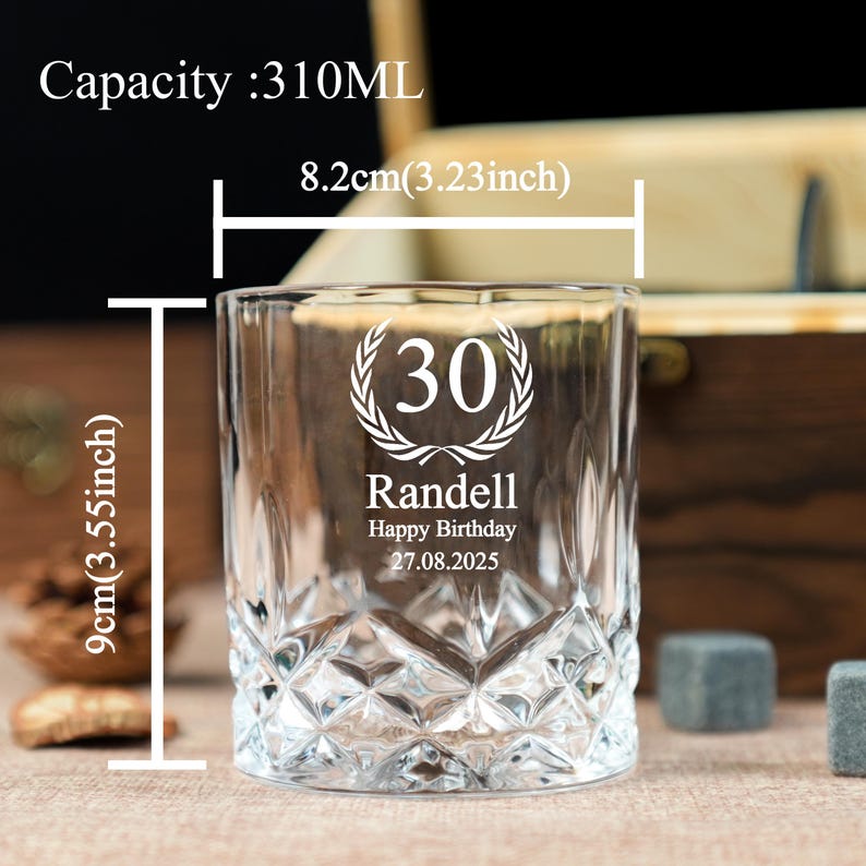May include: A clear, personalized whiskey glass with a diamond-cut design. The glass is 3.55 inches tall and 3.23 inches wide, with a capacity of 310ML. It features the number "30" inside a laurel wreath, the name "Randell", and the text "Happy Birthday 27.08.2025".