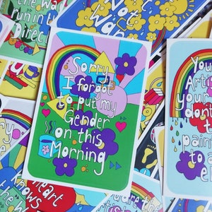 May include: A collection of colourful cards with positive messages. One card features a rainbow and the text "Sorry I forgot to put my Gender on this Morning". Another card features a rainbow and the text "You are the Artist of your own life don't Hand the paintbrush to anyone else".
