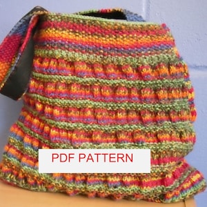 May include: A colourful knitted bag with a black strap and a ruffled bottom. The bag is made with a variety of colours, including red, orange, yellow, green, and blue. The bag has a label that says "PDF PATTERN".