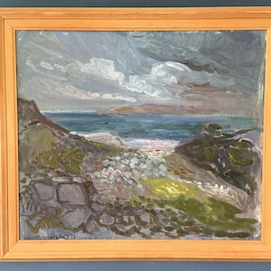 May include: Oil painting of a coastal landscape in a light wood frame. The artwork depicts a beach scene with a stone wall in the foreground, a body of water, and a cloudy sky. The artist's signature and the year '71 are visible.