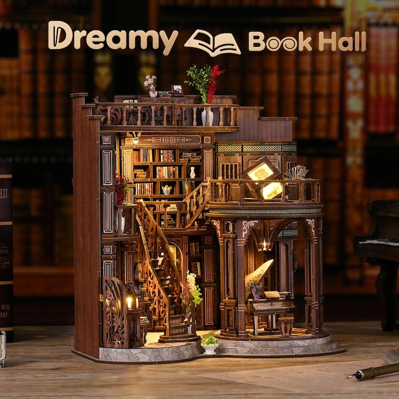 May include: A detailed wooden miniature of a library, featuring multiple levels, staircases, and bookshelves filled with tiny books. The model has warm lighting, creating a cozy atmosphere. The text "Dreamy Book Hall" is displayed at the top.