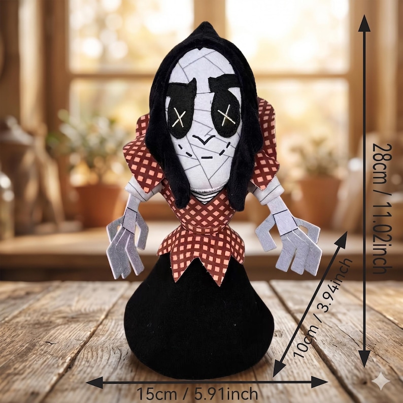 May include: A plush doll featuring a white face with black stitched X-shaped eyes and a black hood. It wears a red and white checkered collar and bodice over a solid black base. Dimensions are 28 cm (11.02 inches) tall, 15 cm (5.91 inches) wide, and 10 cm (3.94 inches) deep.