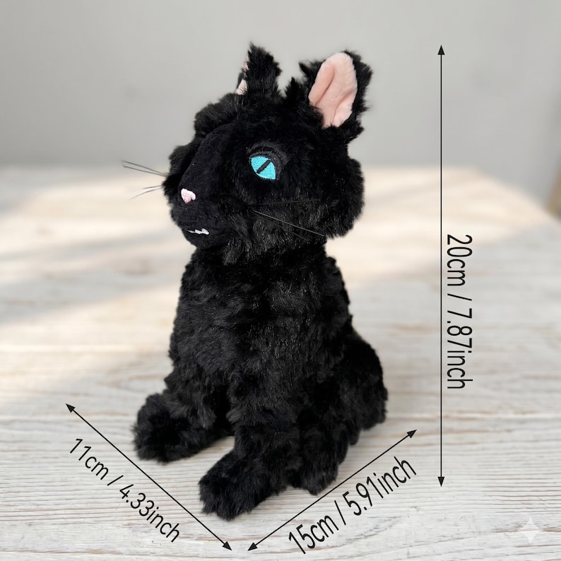 May include: A black plush cat toy with bright blue eyes, a small pink nose, and visible whiskers. The toy measures 20 cm (7.87 inches) in height, 11 cm (4.33 inches) in width, and 15 cm (5.91 inches) in depth as indicated by measurement markers.