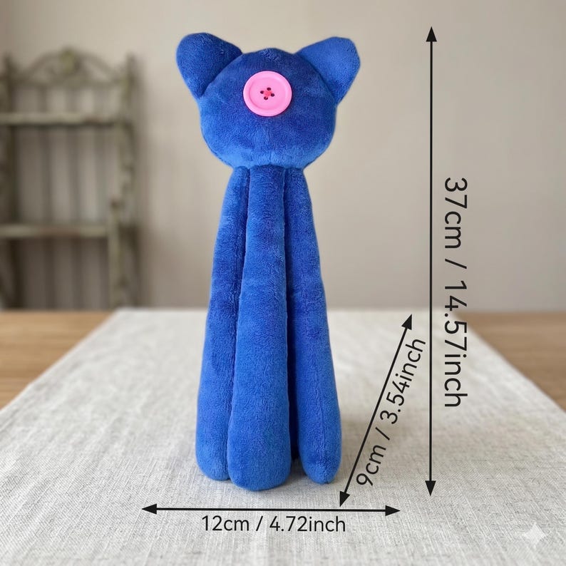 May include: A blue plush cat toy with a pink button eye, measuring 14.57 inches in height, 3.54 inches in depth, and 4.72 inches in width. The soft, textured fabric forms a tall, slender body with pointed ears and a rounded head shape.