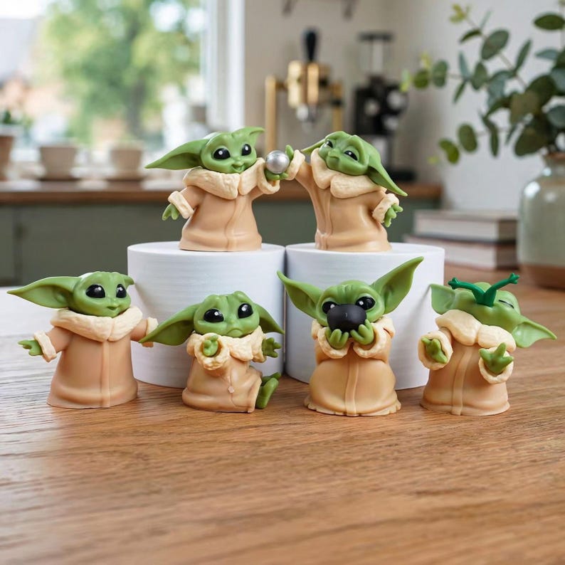 K&ouml;nnte beinhalten: Ein Set aus sechs kleinen gr&uuml;nen Alien-Figuren mit gro&szlig;en schwarzen Augen und spitzen Ohren, die jeweils eine beigefarbene Robe mit cremefarbenem Kragen tragen. Die Figuren nehmen verschiedene Posen ein, einige halten kleine Kugeln in den H&auml;nden.