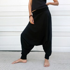 May include: Black harem pants with a wide leg and a gathered waist. The pants are made of a soft, comfortable fabric and have a relaxed fit.