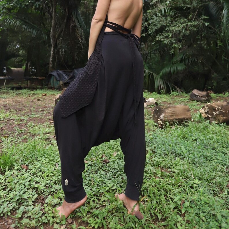 May include: Black harem pants with a loose, flowing fit. The pants have a unique design with a gathered waist and a wide leg.