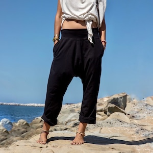 Puede incluir: Pantalones de harén negros de corte amplio y cómodo. Los pantalones tienen una cintura baja y una silueta holgada y fluida. La tela es suave y ligera, lo que los hace perfectos para el clima cálido.