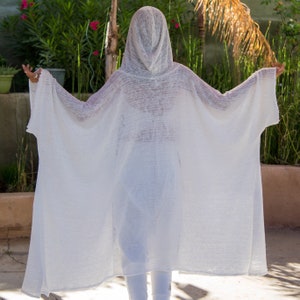 May include: A white hooded linen cardigan with a loose, flowing fit. The cardigan is made of a lightweight, breathable fabric and has a relaxed, comfortable style.