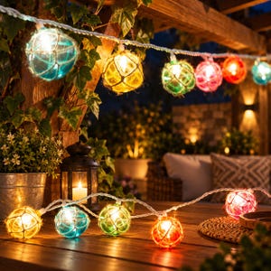 May include: A string of decorative globe lights featuring round glass spheres wrapped in natural twine netting. The lights emit a warm glow in various colors including blue, yellow, green, and red, suspended from a white cord in an outdoor setting.