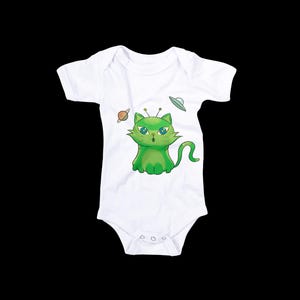 May include: White baby onesie featuring a green cartoon cat with alien antennae and a surprised expression. The cat is surrounded by a planet and a flying saucer. A cute and whimsical design for infants.