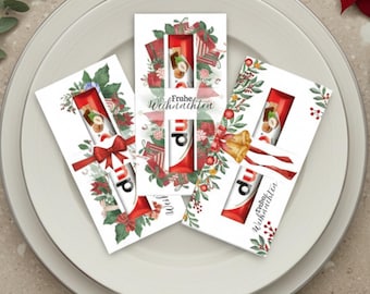May include: Three Christmas-themed gift cards with a red and white candy bar visible through a window. The cards are decorated with festive elements like bows, bells, and greenery. The words "Frohe Weihnachten" are printed on one of the cards.
