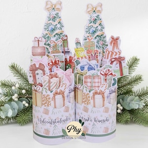 May include: A Christmas advent calendar with two cylindrical structures decorated with illustrations of wrapped gifts, candy canes, and Christmas trees. The design uses pastel colours, bows, and the text "Adventkalender" and "24 süße Wünsche".