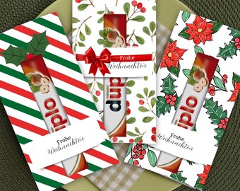 May include: Three festive Christmas-themed gift card holders with chocolate bars. One holder has red and green diagonal stripes, another has a floral design with a red bow, and the third has poinsettias and holly. Each has a chocolate bar peeking out.