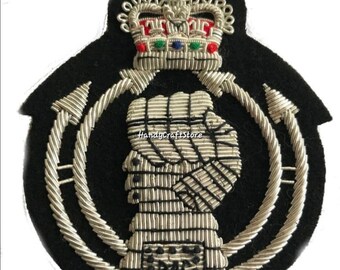 May include: A black embroidered patch featuring a crown with red, green, and blue accents. The patch includes a profile of a person and the letters "RAC" in silver thread, surrounded by a silver rope design.