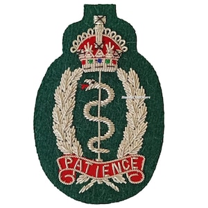May include: A green embroidered patch featuring a silver caduceus symbol, a red and gold crown, and the word "PATIENCE" in red lettering. The patch has a dark green felt background and silver embroidered details.