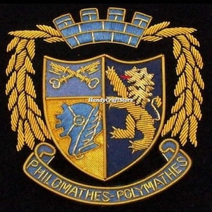 May include: Embroidered crest with a blue and gold color scheme. The crest features a crown, laurel branches, and a shield divided into quadrants with various symbols, including a lion and crossed keys. The text "PHILOMATHES-POLYMATHES" is arched below.
