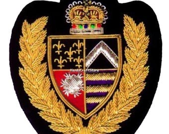 May include: Embroidered crest with a black background, gold laurel wreath, and a detailed shield. The shield features a crown, fleur-de-lis, and other heraldic symbols. The text "HandyCraftStore" is visible.