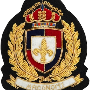 May include: A black embroidered patch featuring a heraldic crest with a crown, laurel leaves, and a banner with the word "ARCONOMI". The crest has red, white, and blue sections with a gold fleur-de-lis.
