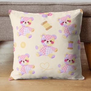 K&ouml;nnte beinhalten: Ein quadratisches Dekokissen mit cremefarbenem Hintergrund und einem wiederkehrenden Muster aus Teddyb&auml;ren im Patchwork-Stil in Rosa-, Lila- und Gelbt&ouml;nen, durchsetzt mit kleinen Garnrollen, gelben Kn&ouml;pfen und gestrichelten Herzumrissen.