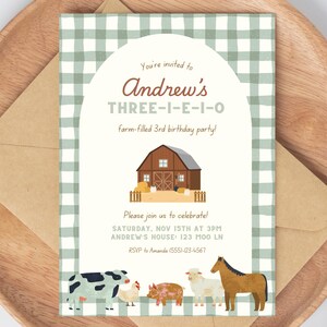 May include: A farm-themed birthday party invitation featuring a barn illustration, farm animals, and the text "Andrew's THREE-I-E-I-O farm-filled 3rd birthday party!" The invitation is on a wooden tray with a brown envelope.