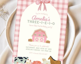 May include: A pink and white gingham-patterned invitation for Amelia's third birthday party. The invitation features a pink barn illustration, a pink bow, and farm animal illustrations. The text reads "Amelia's THREE-I-E-I-O Farm-filled 3rd birthday party!"