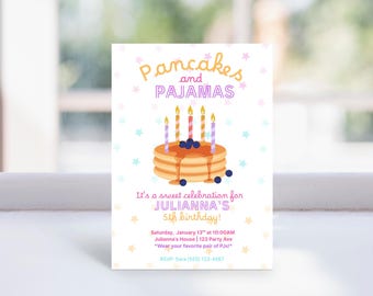 May include: A rectangular invitation card with the text "Pancakes and Pajamas" in pink and yellow. The card features a stack of pancakes with syrup, blueberries, and lit candles. The text below reads "It's a sweet celebration for Julianna's 5th birthday!"