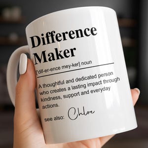 May include: A white ceramic mug featuring black printed text that defines the noun Difference Maker as a thoughtful and dedicated person who creates a lasting impact through kindness, support, and everyday actions, with the name Chloe listed below.