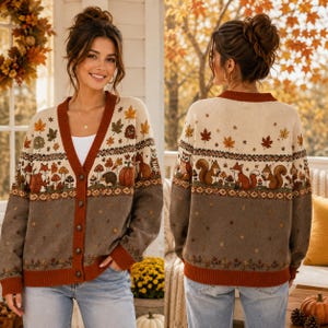 May include: A long-sleeve button-down cardigan featuring a cream-coloured upper section with a pattern of autumn leaves, mushrooms, pumpkins, hedgehogs, owls, and squirrels, transitioning into a solid brown lower section with small leaf accents.