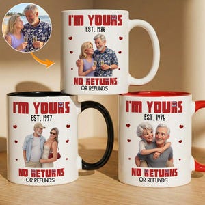 May include: Three white ceramic mugs featuring custom illustrations of couples. Each mug displays the text I'M YOURS, EST. followed by a year, and NO RETURNS OR REFUNDS. The designs include small red hearts and personalized portraits of couples.